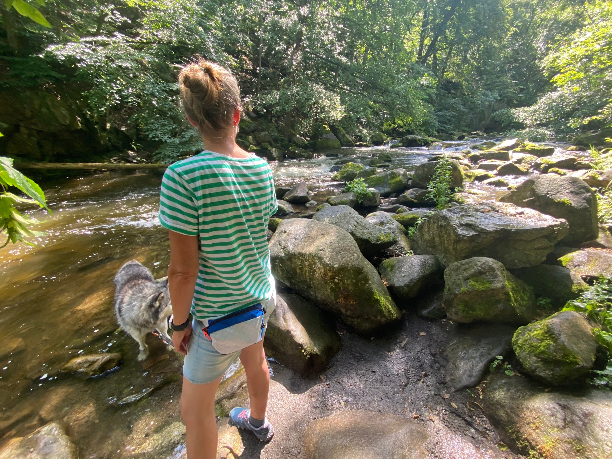 Frau trägt blau-weiße ultraleichte Hüfttasche am Fluss, die Farben hat sie sich selbst ausgesucht